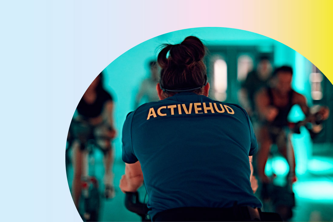 Back of instructor in a fitness class, with ActiveHud written on shirt of instructor in focus