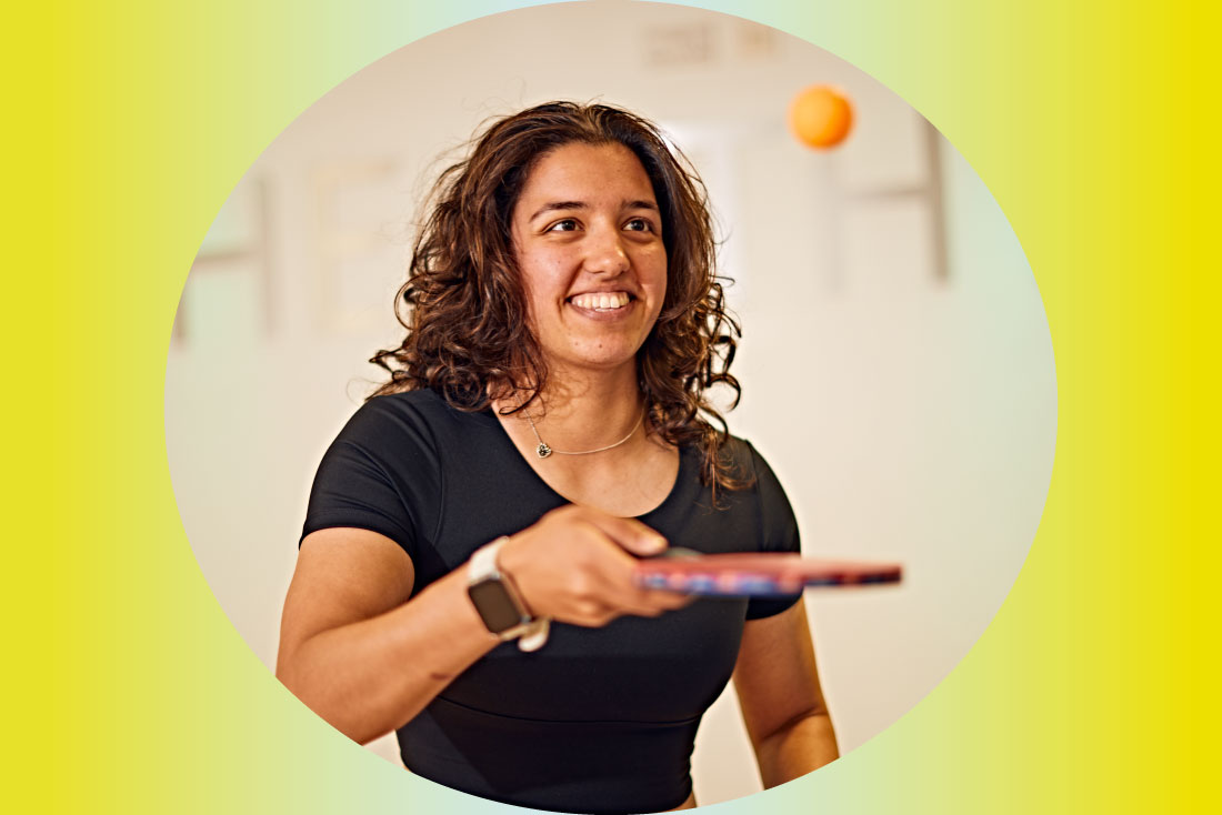 Student playing table tennis, holding racket and ball
